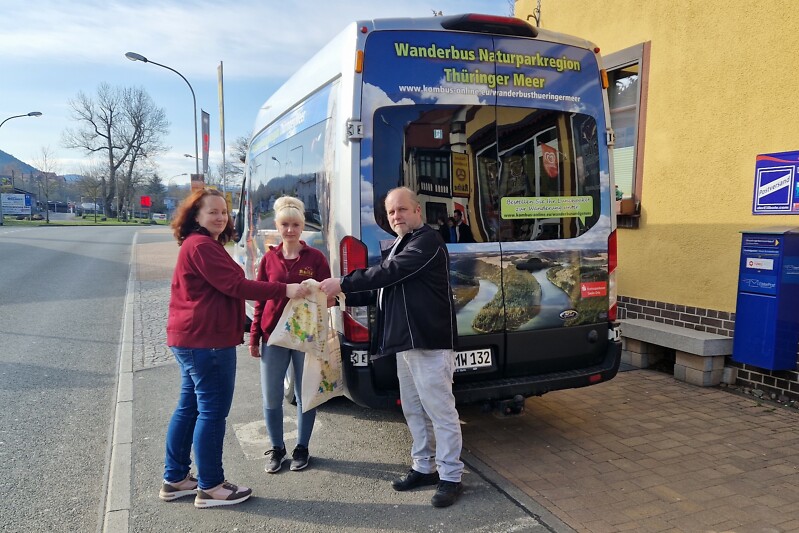 Mitarbeitender der Bäckerei Räthe überreichen einem Busfahrer des Wanderbuses ein Genusspaket Thüringer Meer.